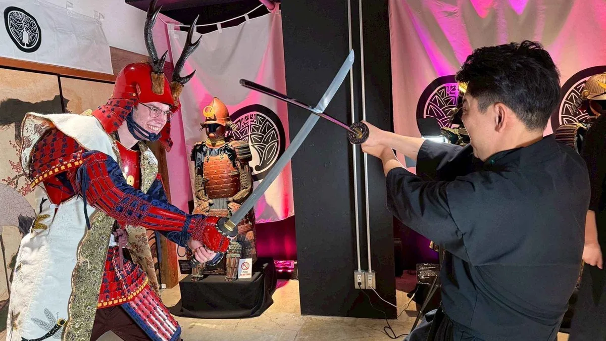 Armored guest writing kanji calligraphy on a war fan during a samurai walk Kyoto photoshoot, Kyoto